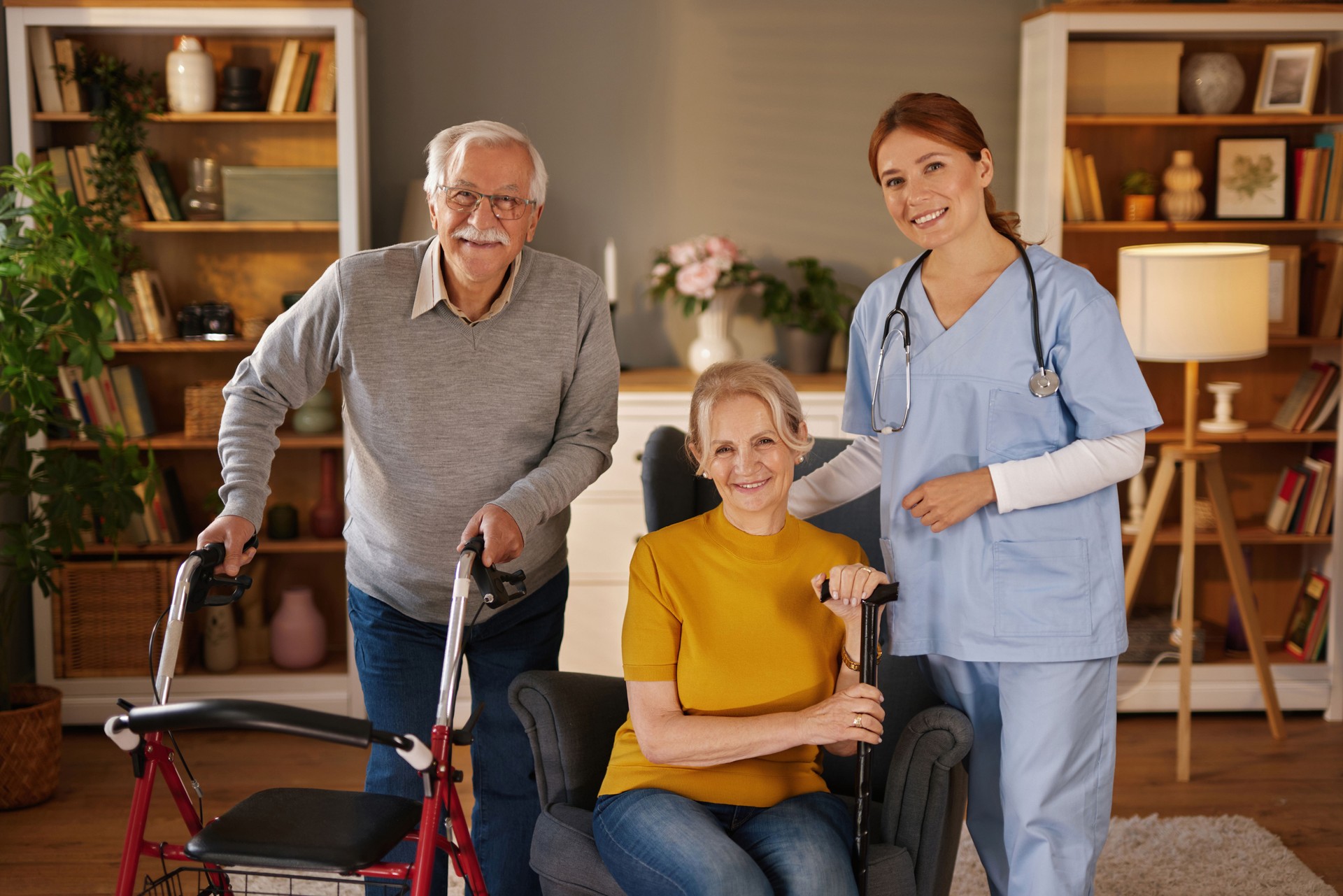 Nurse smiling with elderly couple using walking aids at home
